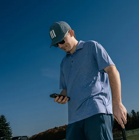Golfer looking at the Tee On tee time booking app on a smartphone